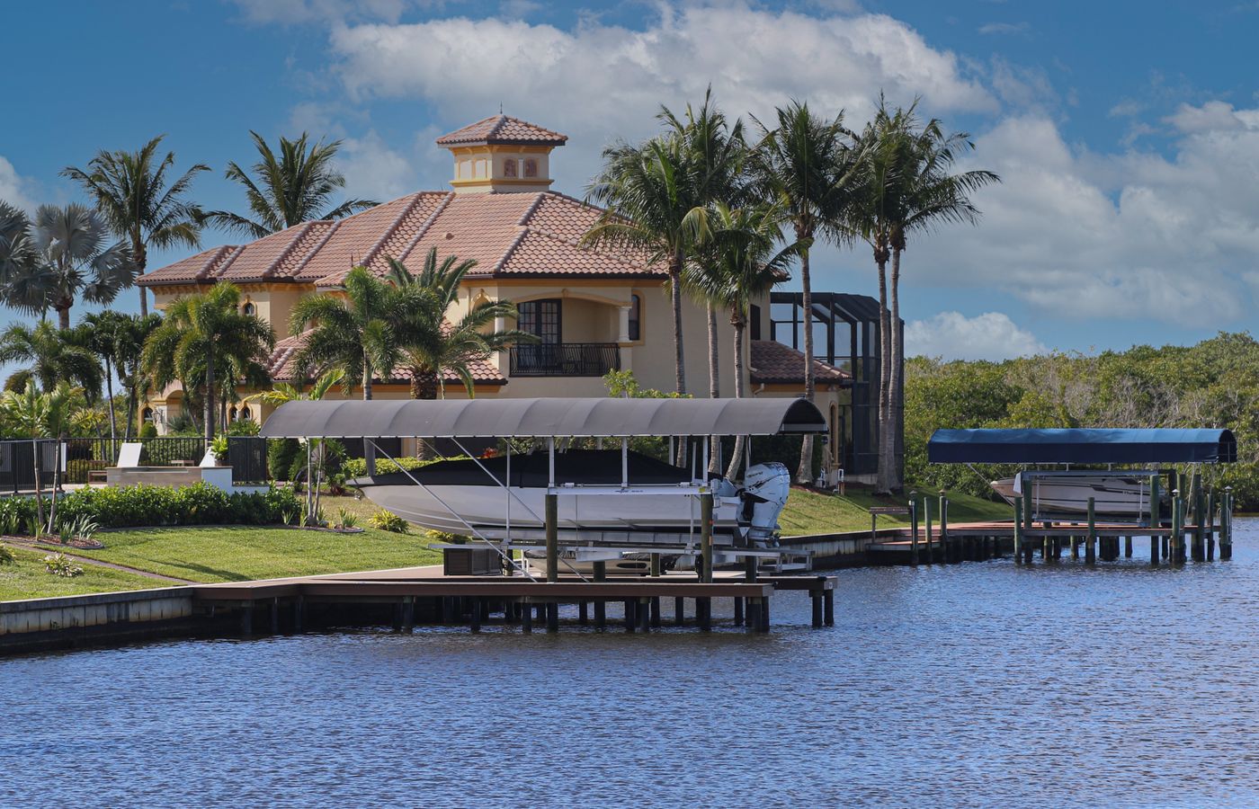 Waterfront wall beside a Cape Coral home with docks and covered boat lifts.