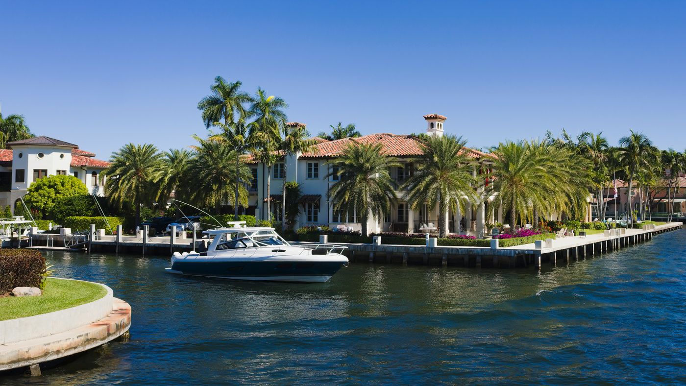 A boat passing canal-front homes, waterfront walls and dock posts in Fort Lauderdale.